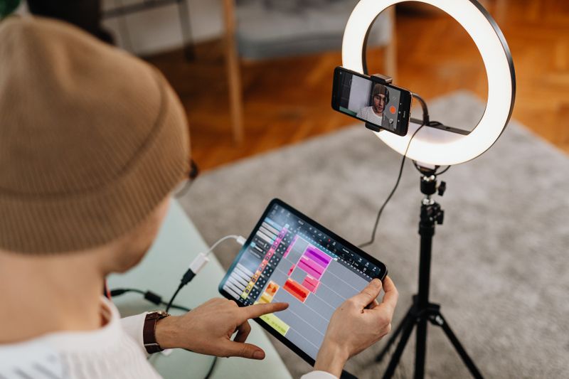 Music creator preparing multiple promotional videos with a smartphone and tablet