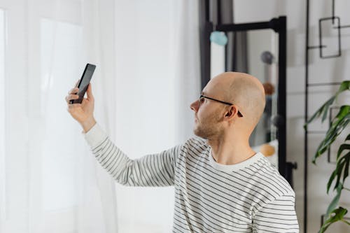 Free A Bald Man Holding a Smartphone Stock Photo