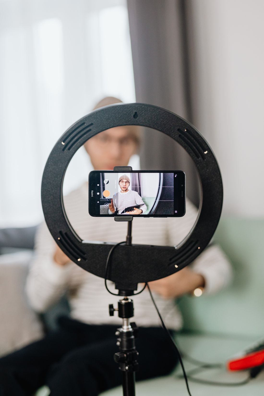 Mann nimmt mit Ringlicht und Smartphone Content auf – Technik und KI ersetzen nicht die eigene Stimme.