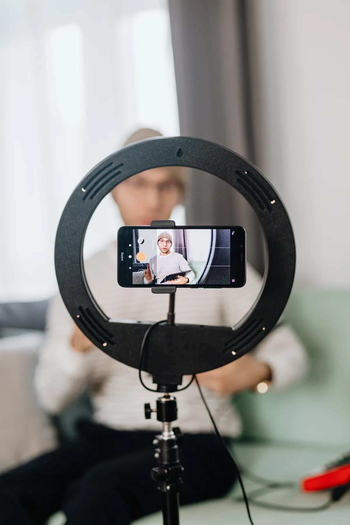Kreator konten merekam vlog menggunakan smartphone dengan tripod dan ring light untuk video cinematic