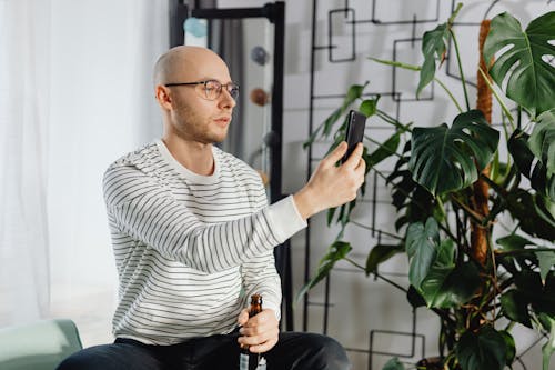 Free A Bald Man Holding a Beer and Smartphone Stock Photo