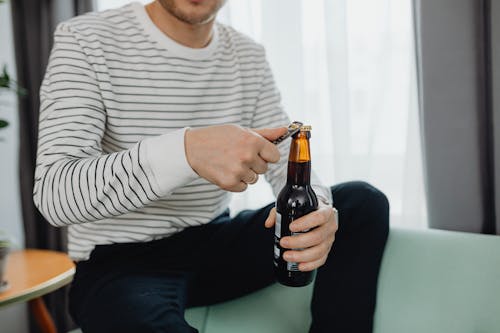 Close-Up Shot of a Person Opening a Beer Bottle