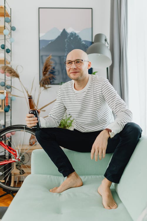 Free A Bald Man Holding a Beer While Sitting on a Sofa Stock Photo