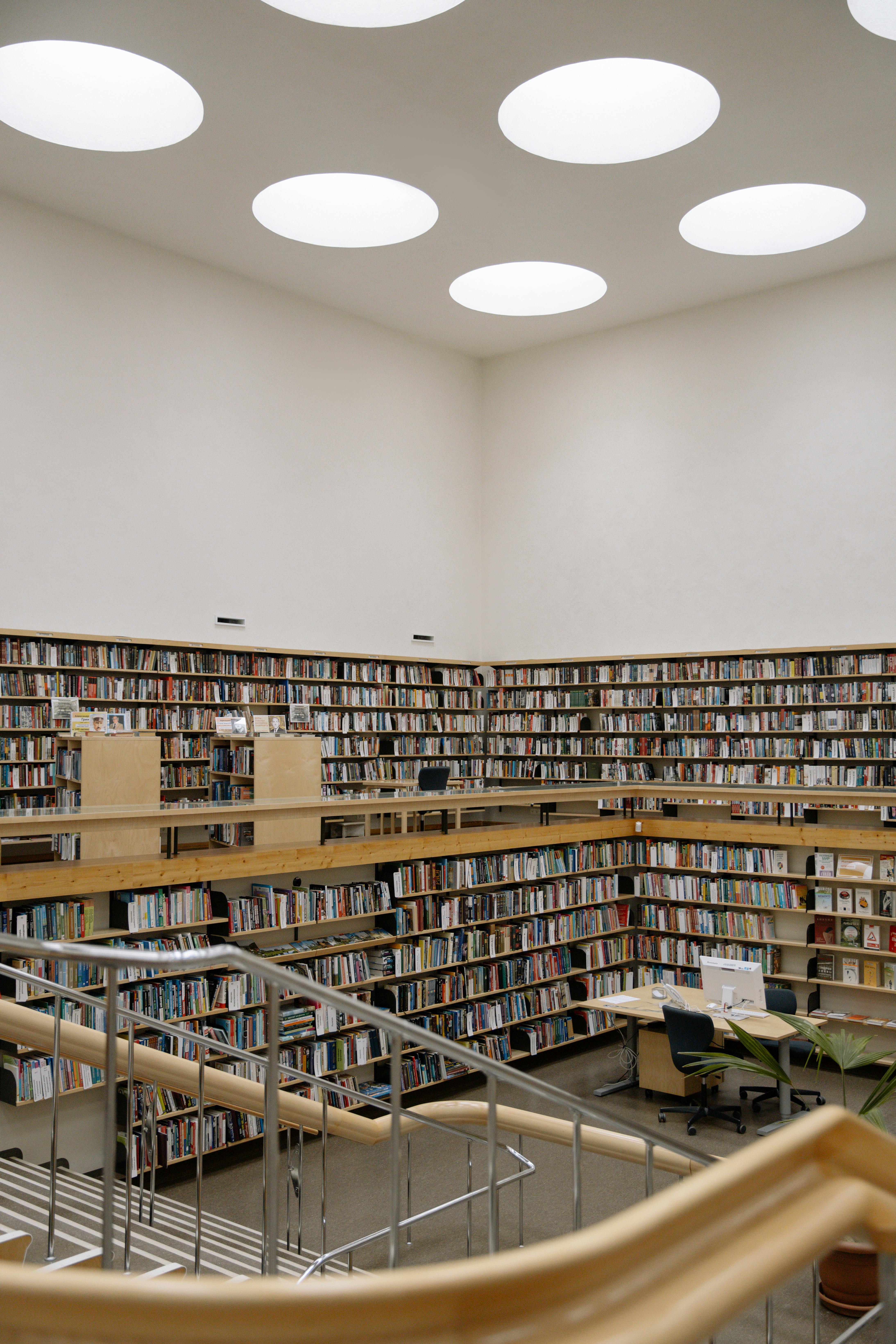 Free A spacious modern library with high bookshelves, skylights, and open reading areas. Stock Photo