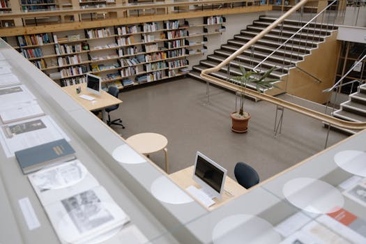Spacious university library interior featuring bookshelves, desks, and a staircase for study and research.