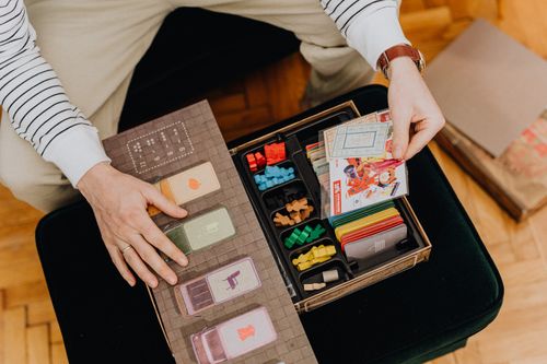 Free High-angle view of a person interacting with a vibrant board game full of cards and pieces. Stock Photo