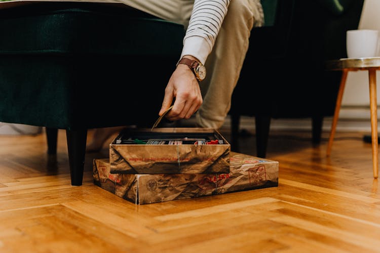 Close-up Of A Man Reaching His Hand Out For Cards From A Board Game Box 