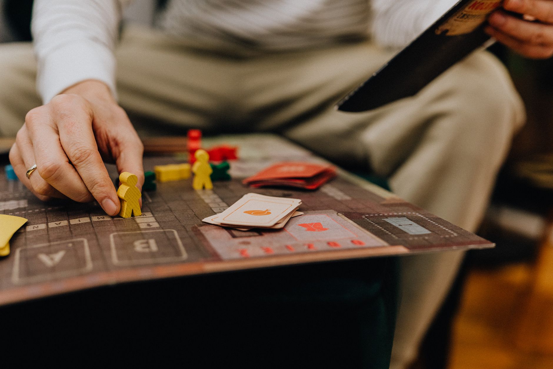 A person is engaged in a board game, focusing on strategic moves with colorful pieces.