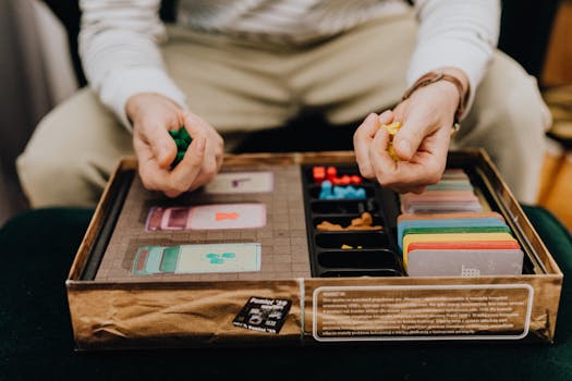 Person playing a board game with colorful pieces and cards indoors, focused and engaging.