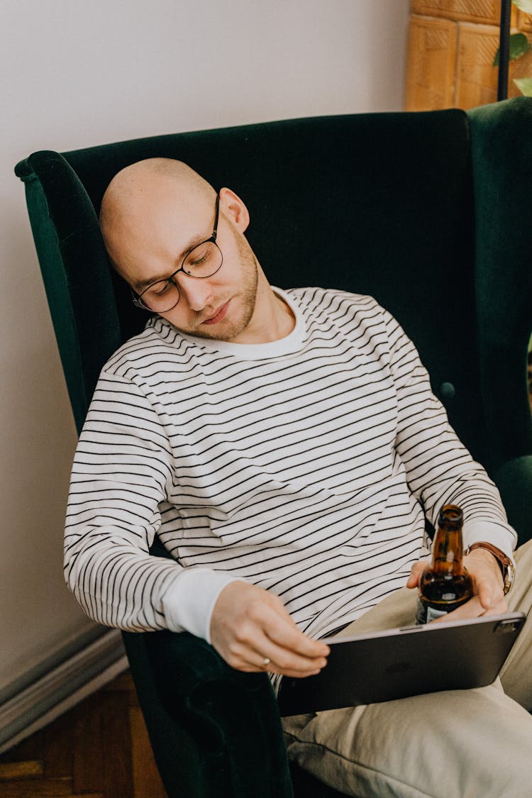 Man Relaxing In Chair With Pad Drinking Beer