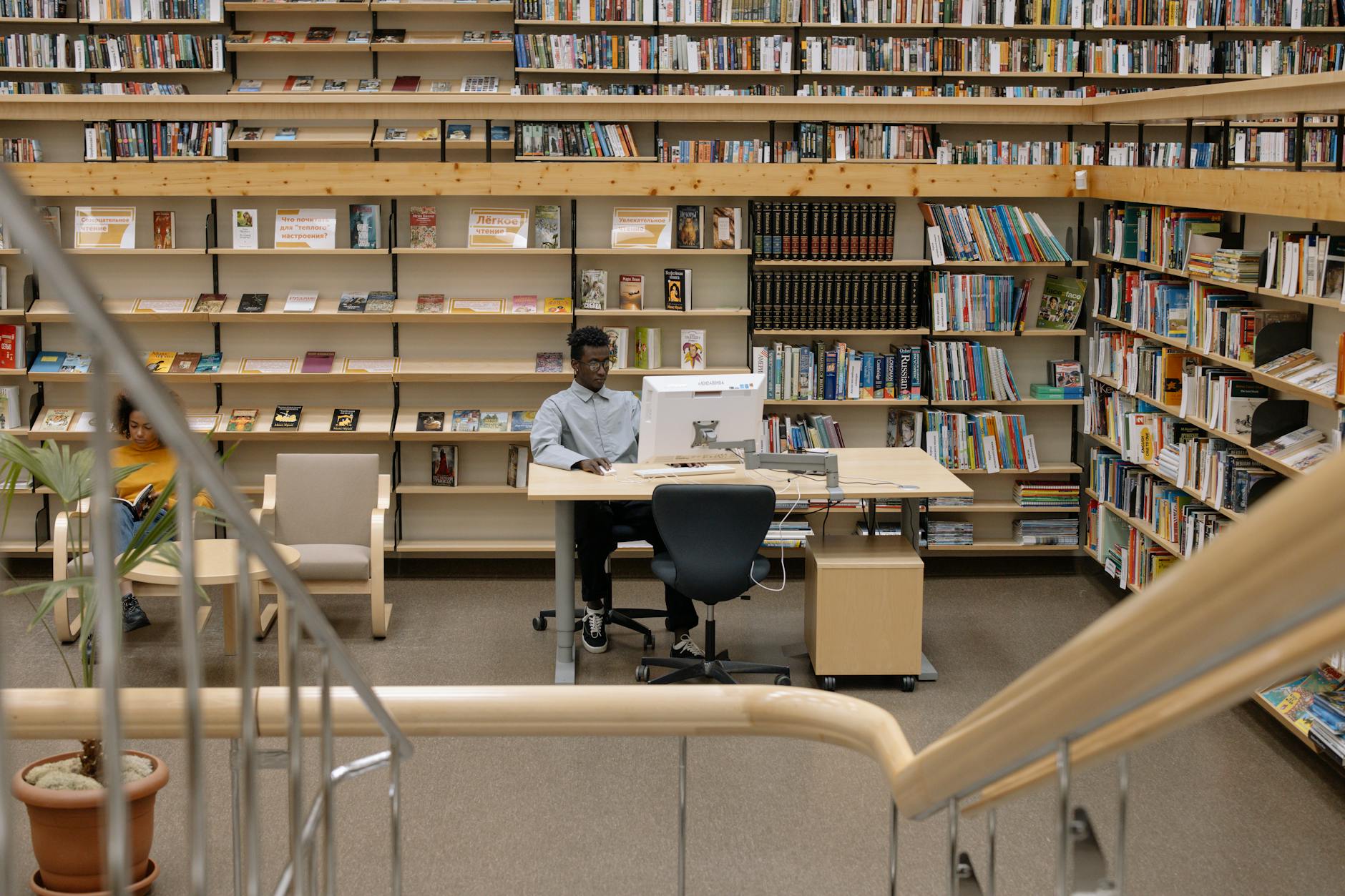 A serene library setting with a man studying and bookshelves filled with diverse literature.