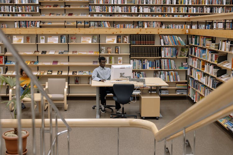 Photo Of Man Using Computer In Library