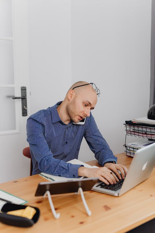 Man Working on Laptop Talking on Cell
