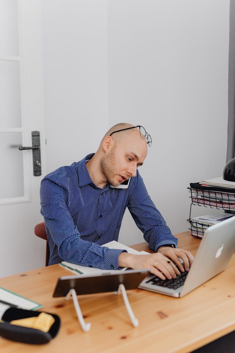 Man Working On Laptop Talking On Cell