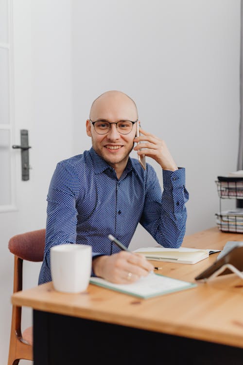 A Man with Eyeglasses Holding a Phone Smiling
