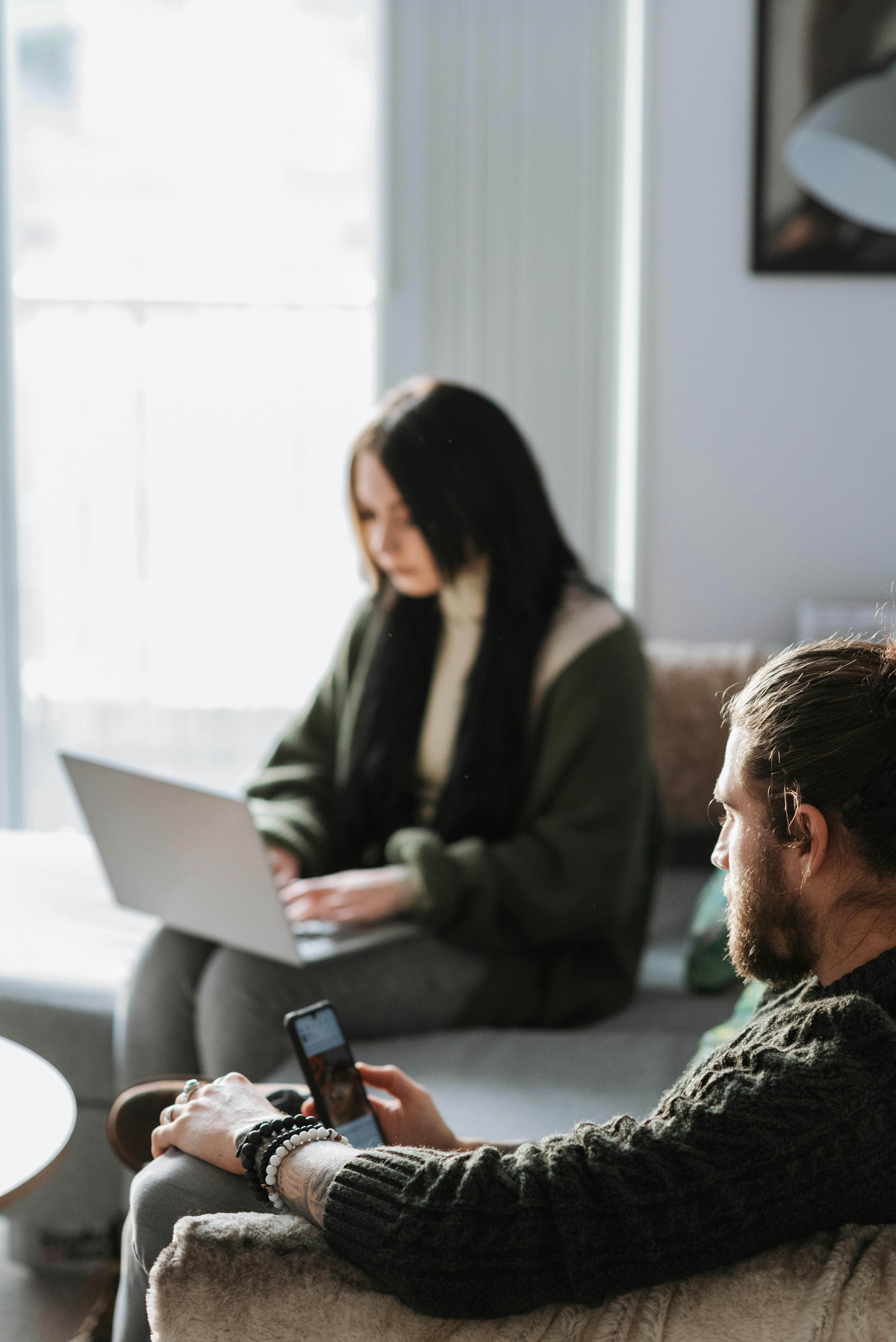 crop man surfing internet on smartphone near girlfriend with laptop