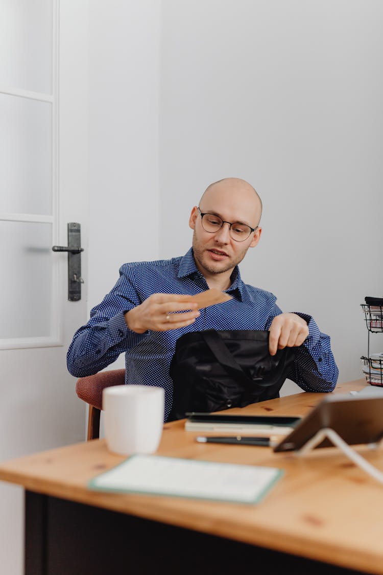 A Man With Eyeglasses Holding A Piece Of Paper