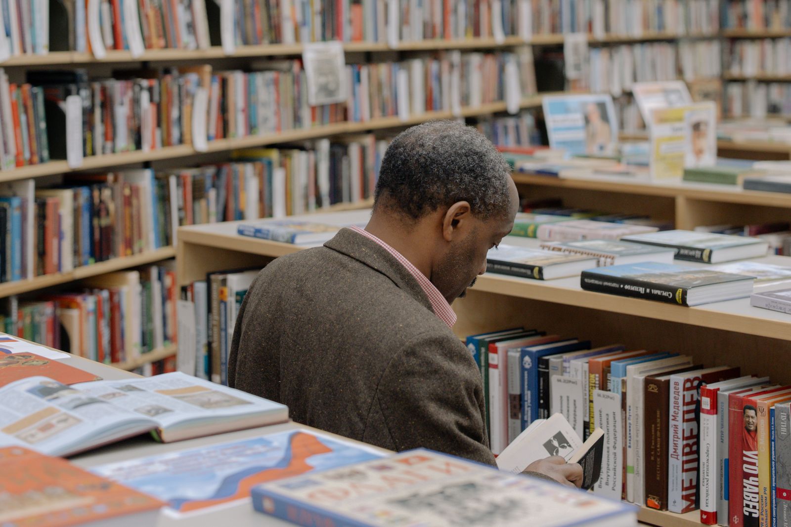 Black reader browsing books in a library