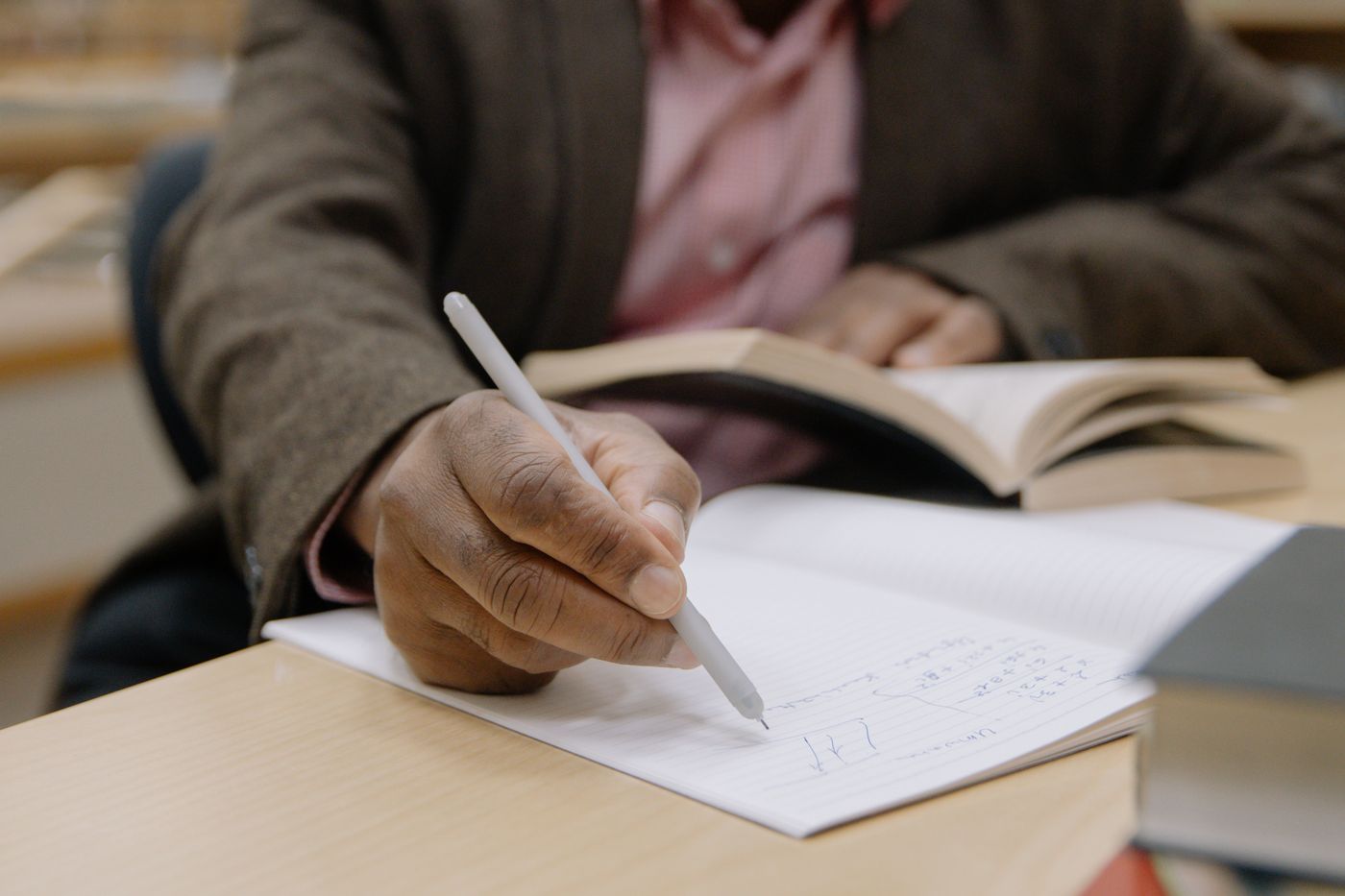 Hand writing notes beside an open book