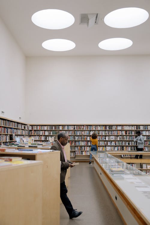 Three People Looking for Books Around the Library