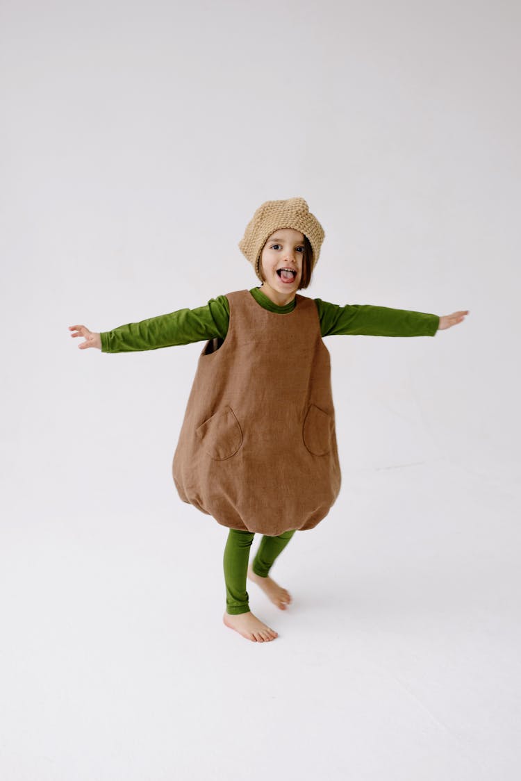 Girl In Brown Loose Romper With Green Leggings And Knit Hat