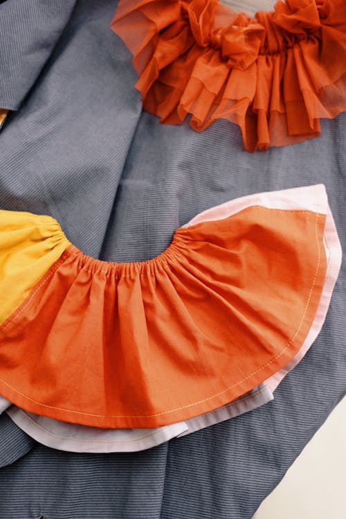 Free Orange and White Ruffled Skirt on Gray Textile Stock Photo