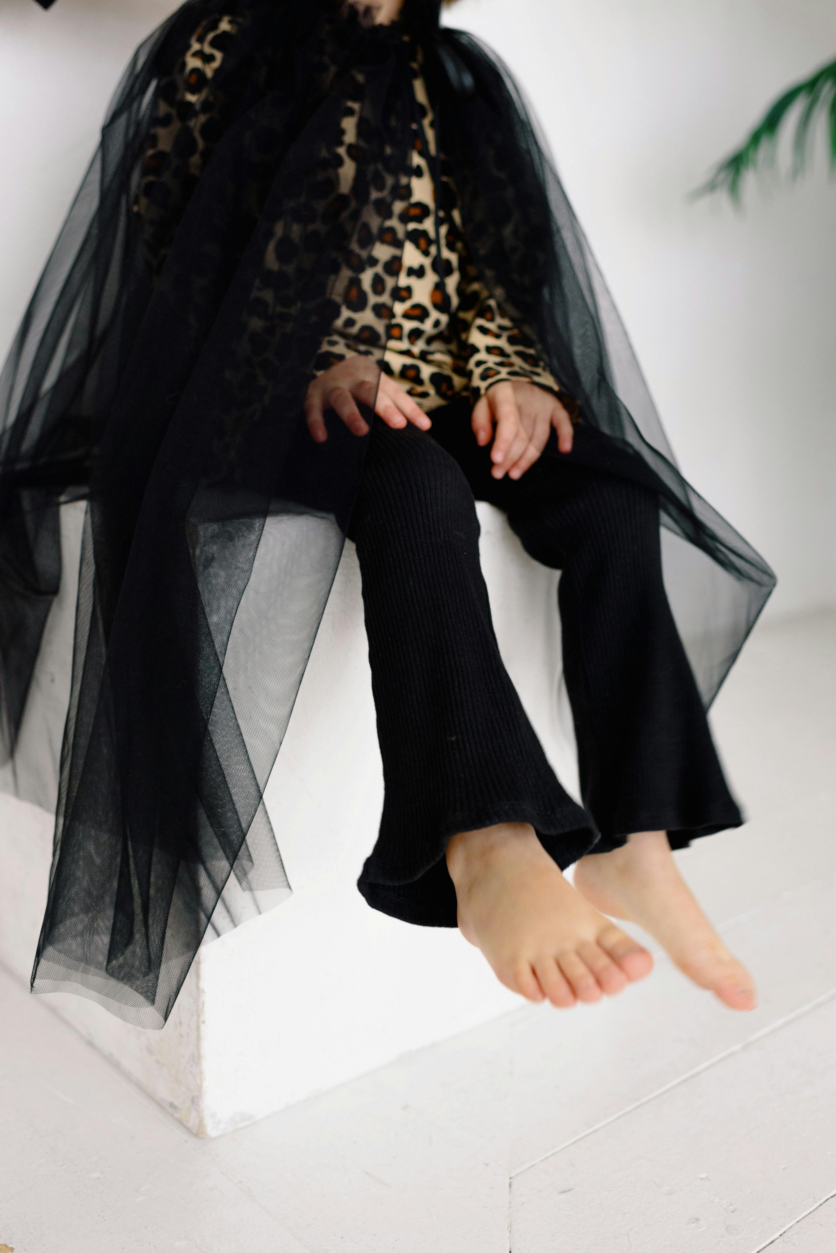 a barefooted kid in costume sitting on a white stool box