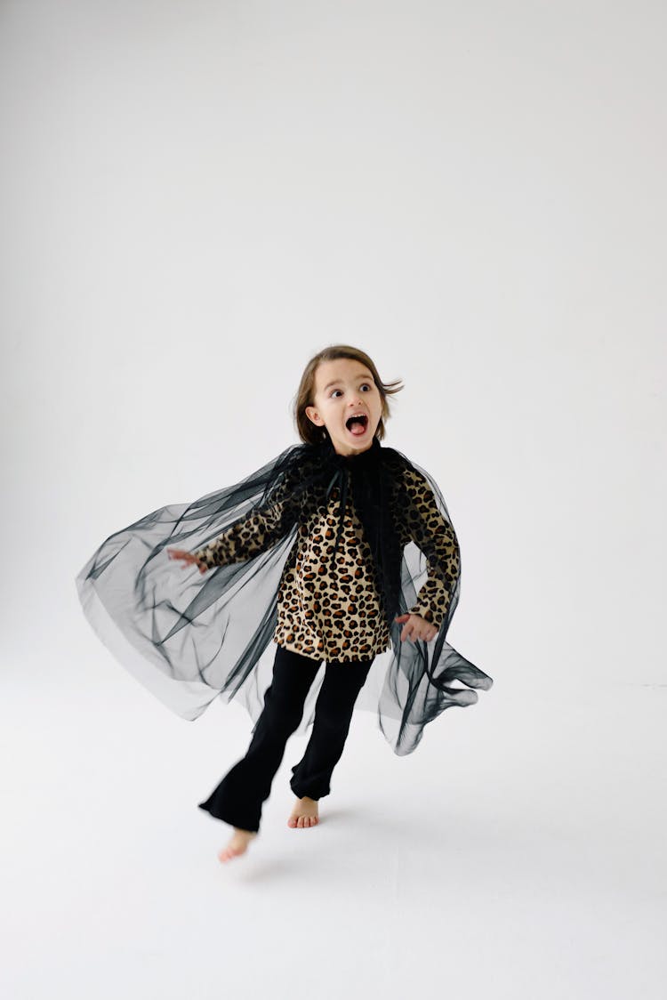 Girl In Leopard Print Long Sleeve Shirt With Black Organza Cloak Running With Mouth Open