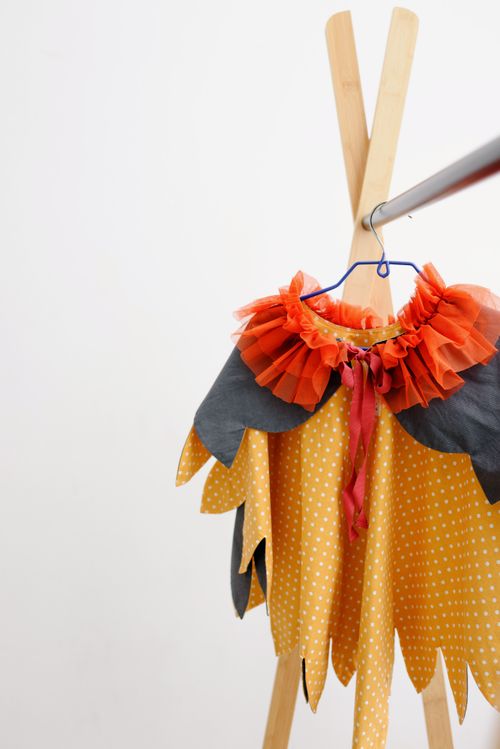 Free Vibrant costume with polka dots and ruffles hanging on a simple wooden rack in a studio setting. Stock Photo