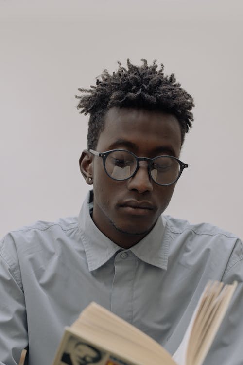 Man in White Dress Shirt with Black Framed Eyeglasses Reading a Book