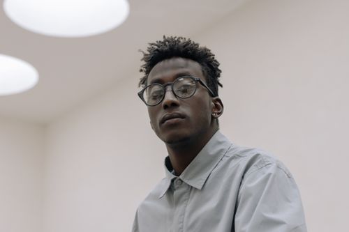 Free Stylish man with curly hair and glasses looking poised. Stock Photo