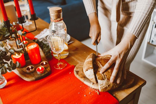 A cozy indoor celebration with a table set with candles and bread being cut.