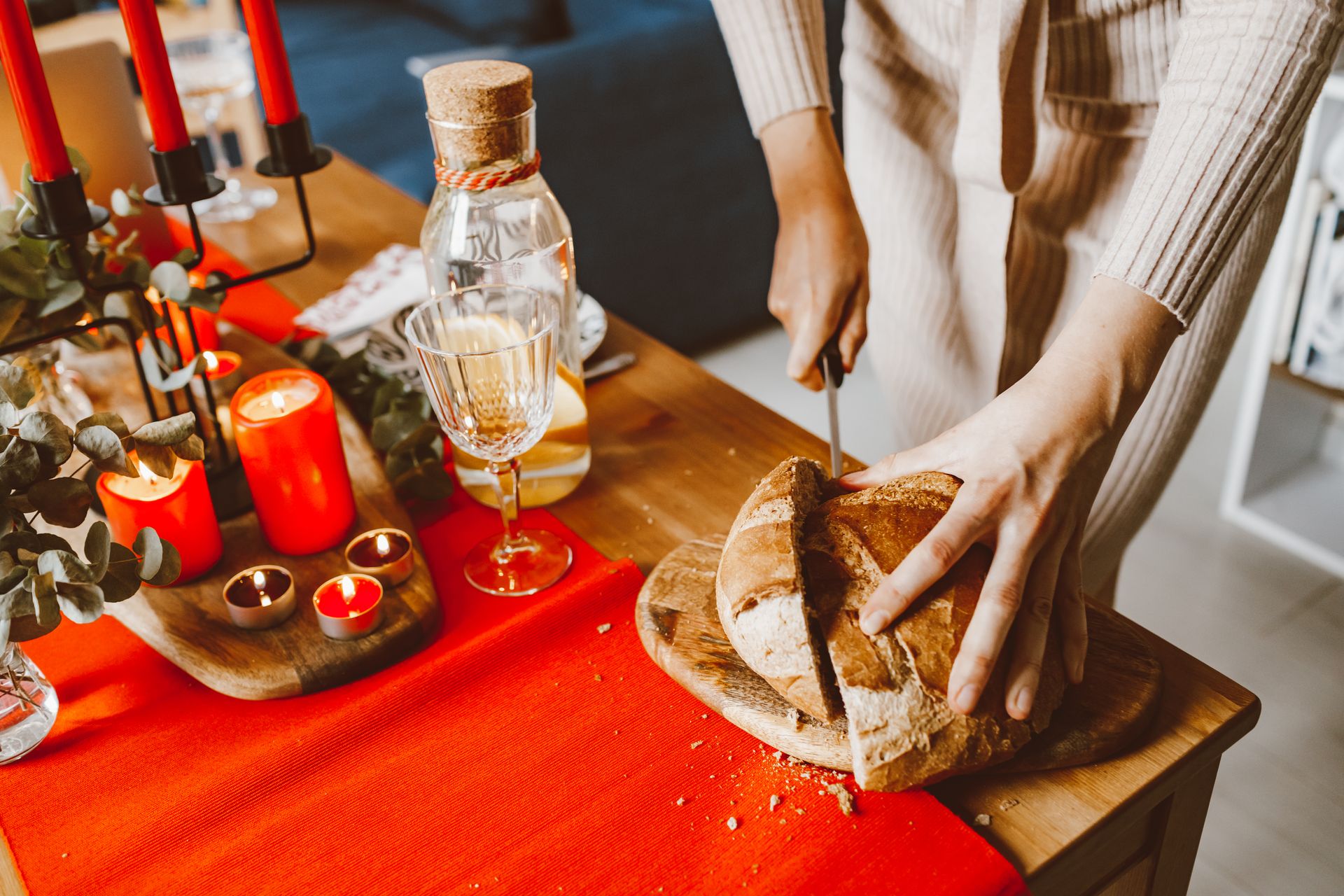 A cozy indoor celebration with a table set with candles and bread being cut.
