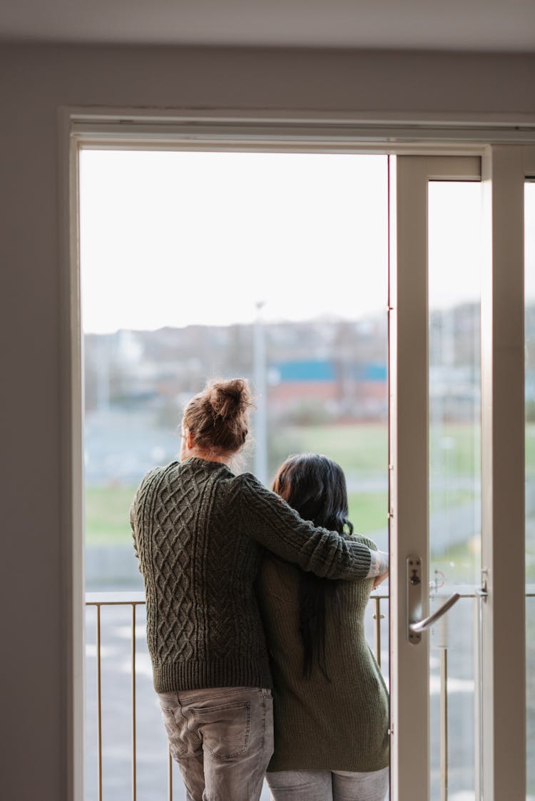 Faceless Couple Embracing On Balcony Against City