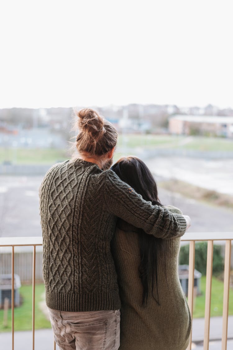 Unrecognizable Couple Embracing And Contemplating City From Balcony