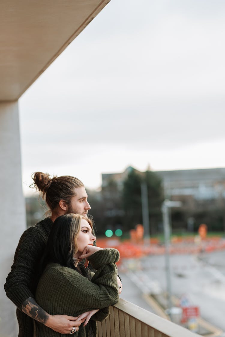 Contemplative Couple Embracing On Balcony Against Town