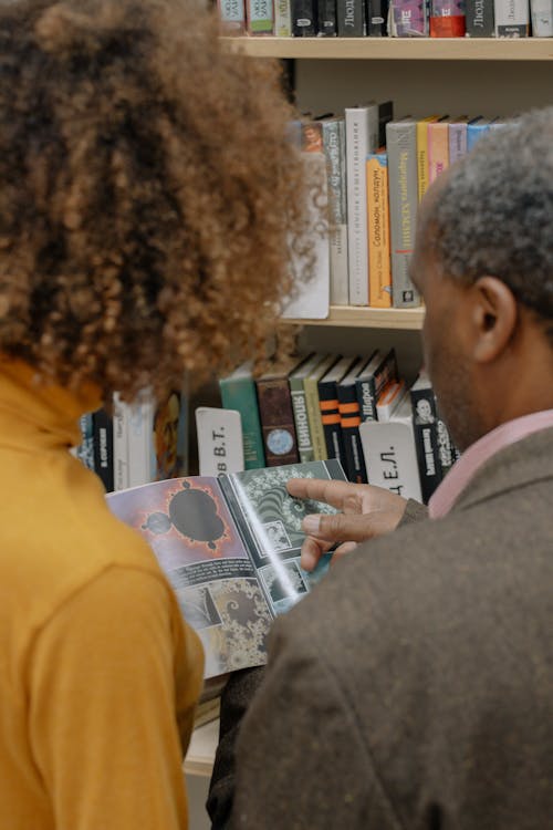 Man in Gray Sweater Holding Books