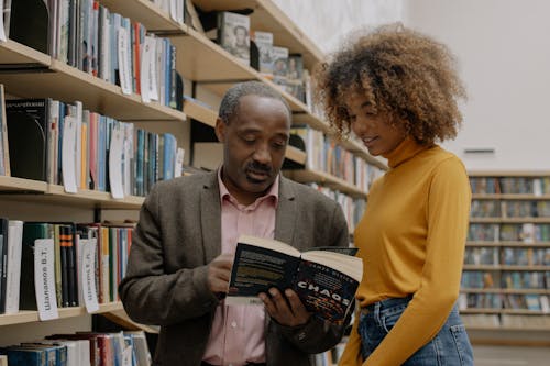 Мужчина в желтом свитере держит книгу рядом с женщиной в коричневом свитере