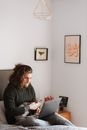 Hipster man with cat surfing internet on laptop on bed