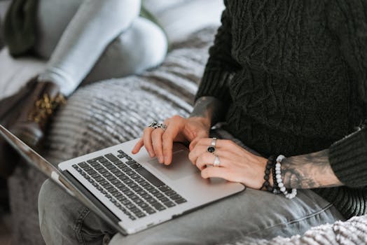 Two young adults working remotely at home with a laptop on a cozy bed.