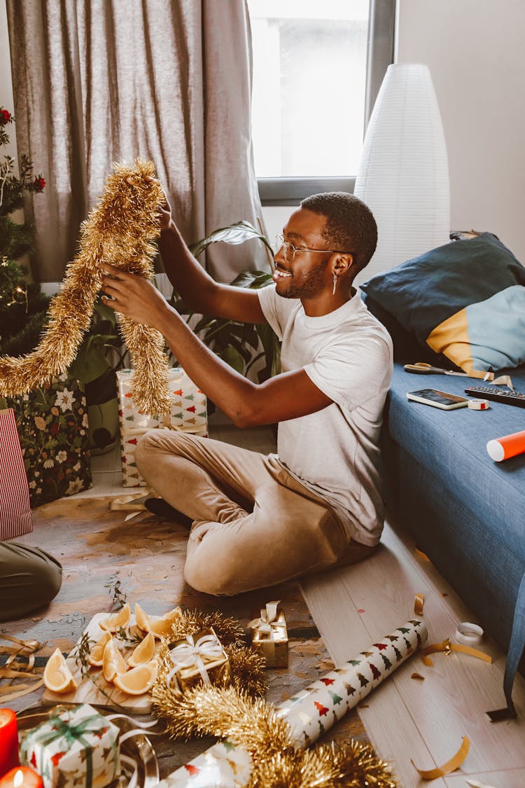 A Man Holding A Gold Tinsel Garland