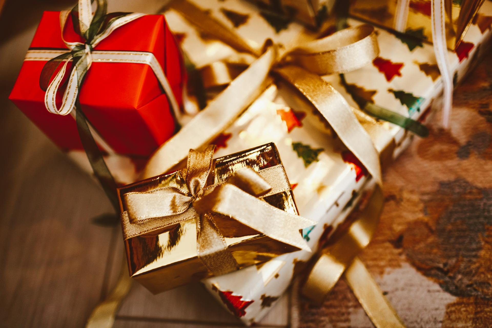 Colorful wrapped Christmas presents with gold ribbons and tree patterns, ideal for holiday celebrations.