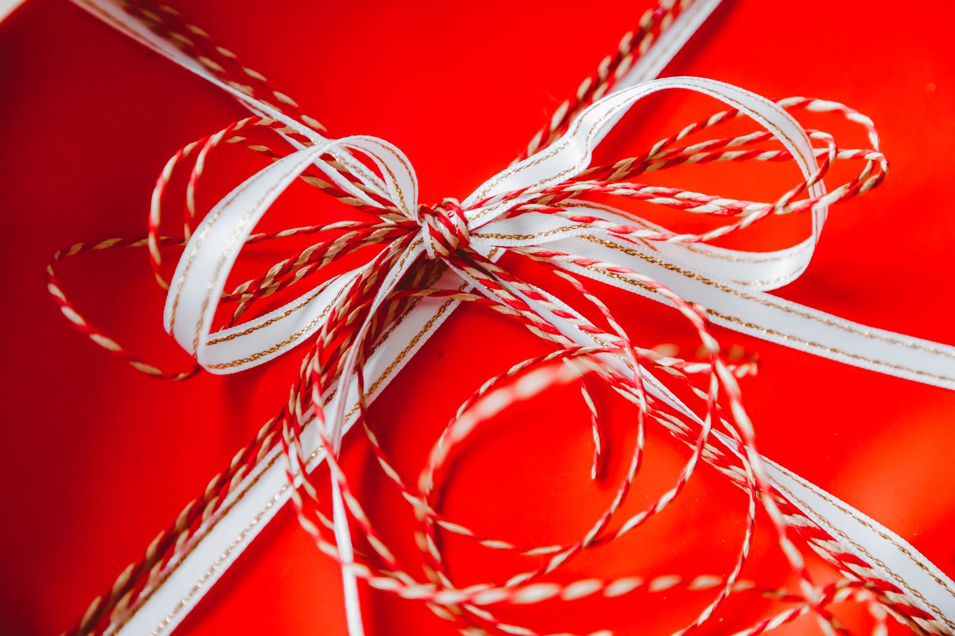 Close-up of a brightly wrapped gift box with festive red and white ribbons.