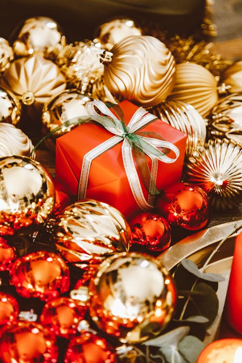 Free Gold and Red Baubles Surrounding a Christmas Gift Stock Photo