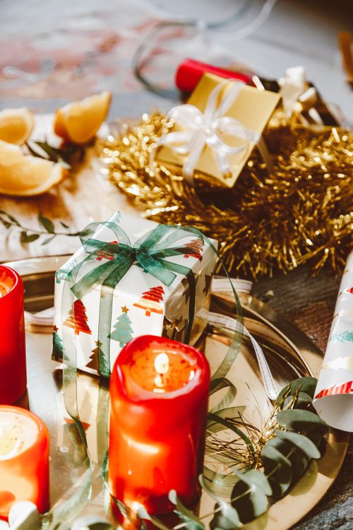 Free Cozy Christmas scene with candles, gifts, and eucalyptus on a metallic tray. Stock Photo