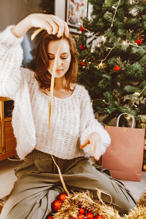 A Woman In White Sweater is Making a Ribbon