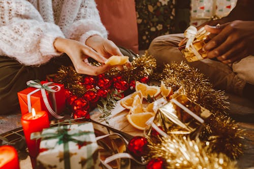 People Preparing Christmas Decors while Eating Orange