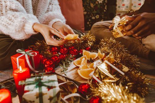 A cozy Christmas setting featuring gifts, oranges, and garlands around candlelight.