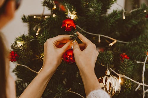 A Person Hanging Bauble on a Christmas Tree