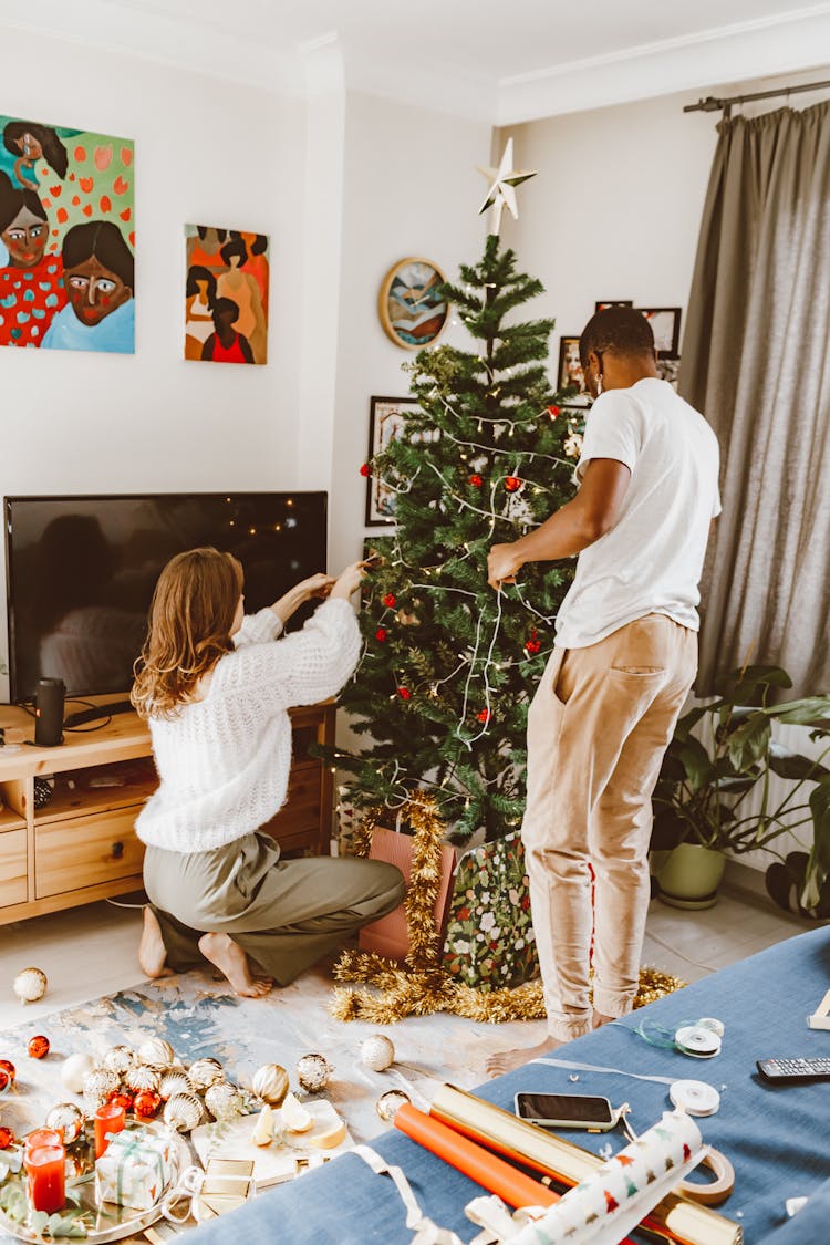 A Couple Decorating A Christmas Tree